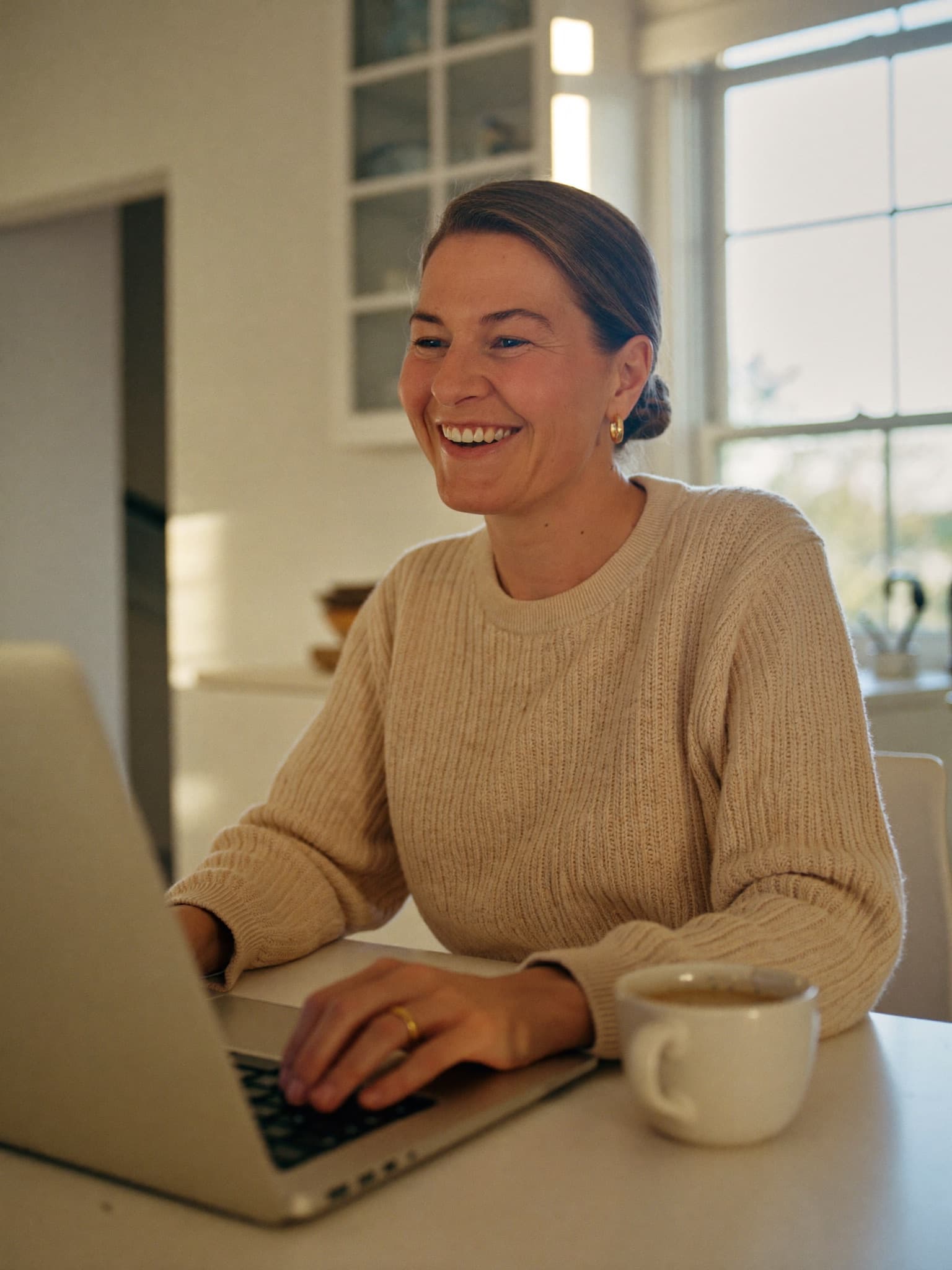 Femme québécoise souriante qui apprend à utiliser l'intelligence artificielle sur son ordinateur, à la maison